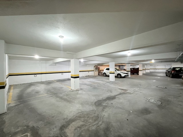Garagem residencial convencional, com paredes brancas e piso de concreto
